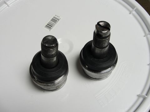 1995 Ford Bronco - Two metal ball joints with rubber boots are shown on a white surface.
