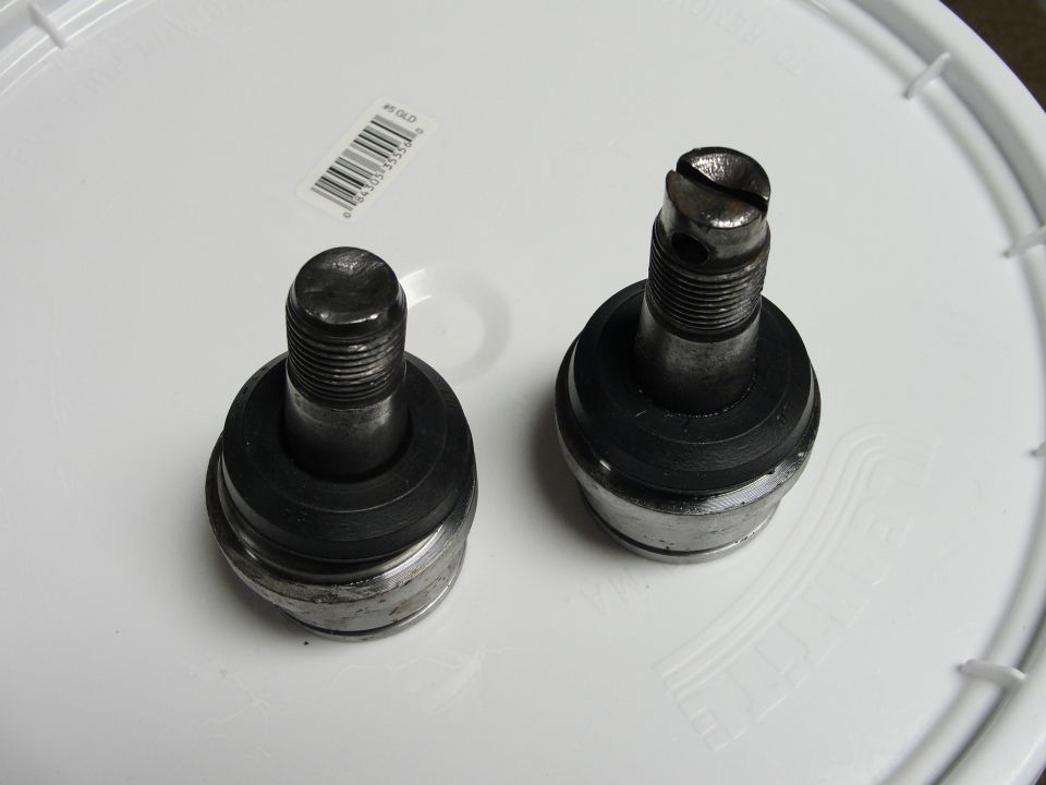 Two metal ball joints with rubber boots on a white surface