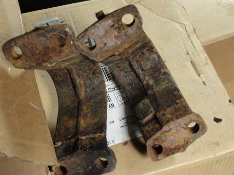 1995 Ford Bronco - Two heavily rusted metal brackets are shown resting on a cardboard box with shipping labels.