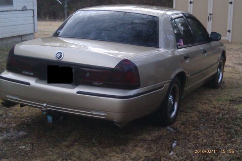 2000 Mercury Grand Marquis - A gold Mercury Grand Marquis sedan is parked outdoors on a dirt lot.