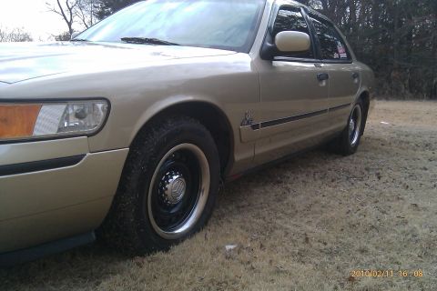 2000 Mercury Grand Marquis - A tan 2000 Mercury Grand Marquis is shown from the front 3/4 angle.