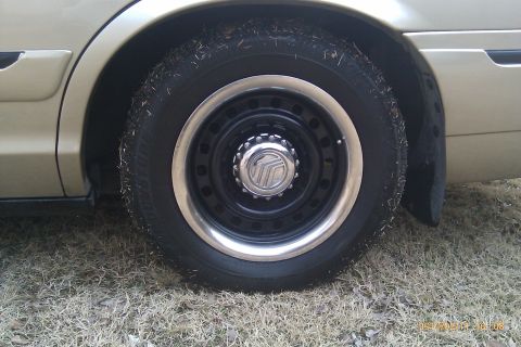 2000 Mercury Grand Marquis - A close-up view of a car's wheel and tire, a Mercury logo on the hubcap.
