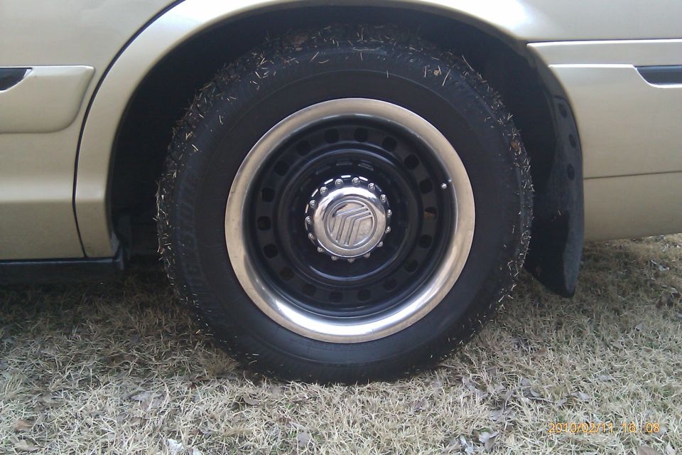 Close-up of a car's wheel and tire with a Mercury logo on the hubcap