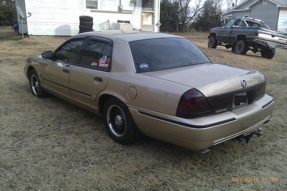 Rear view of a gold Mercury Grand Marquis sedan parked in a rural yard