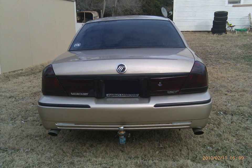 Gold 2000 Mercury Grand Marquis sedan, rear view, with tinted taillights and a trailer hitch