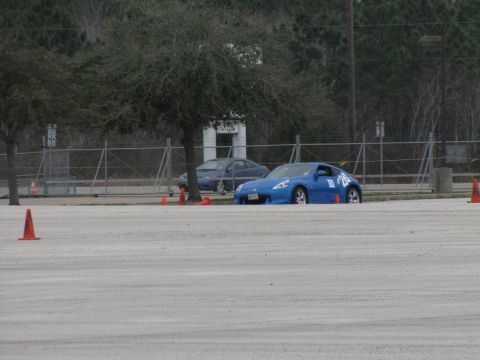2003 Mazda Protege - A blue sports car is parked on a dirt lot, with another car in the background and orange cones around.