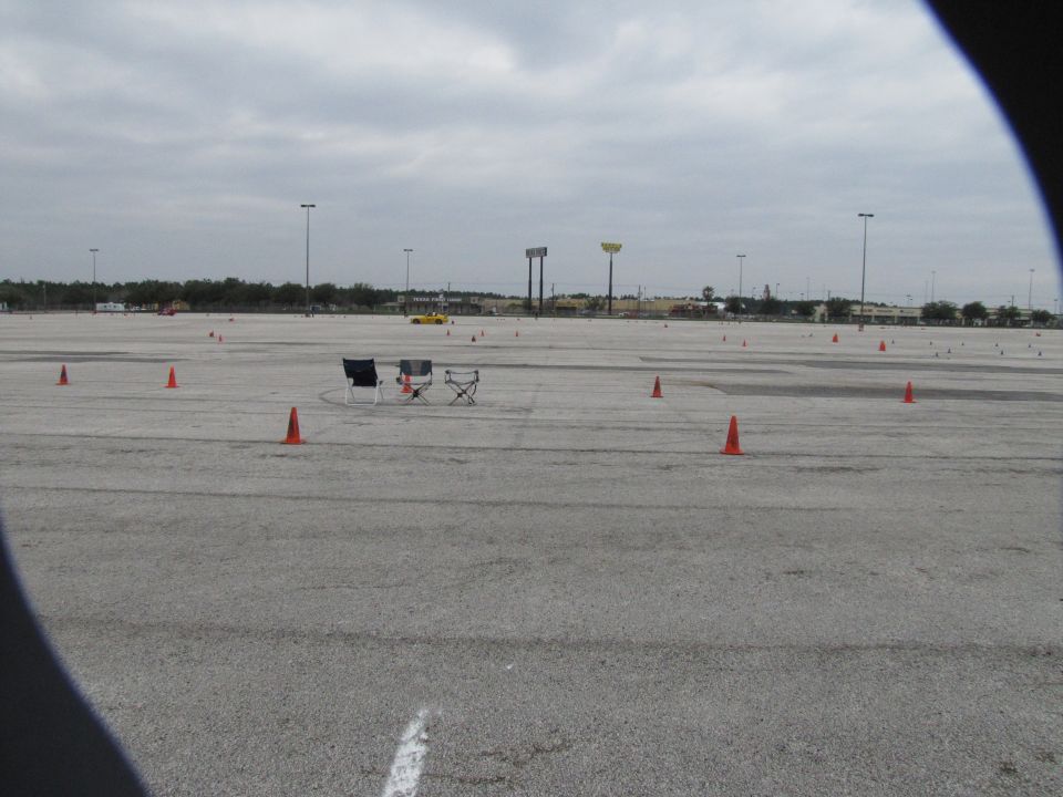 Autocross course setup with orange cones and two chairs on a cloudy day