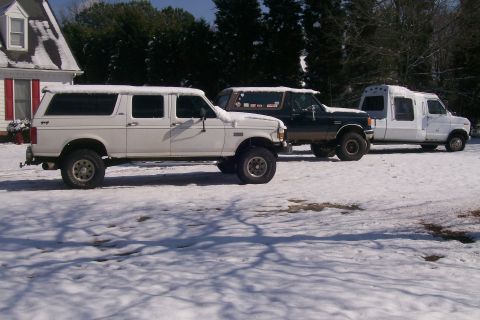 1988 Ford Bronco - A white 1992 Ford Bronco sits in the snow alongside a dark Bronco and a white van.