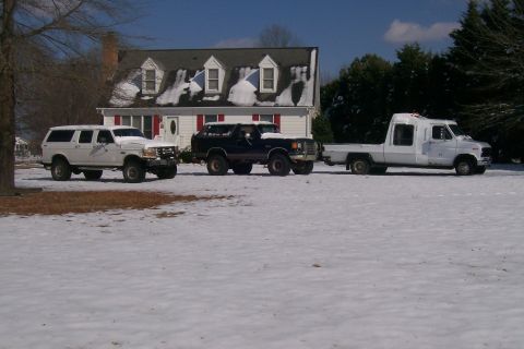 1988 Ford Bronco - Three trucks are parked in the snow in front of a house.