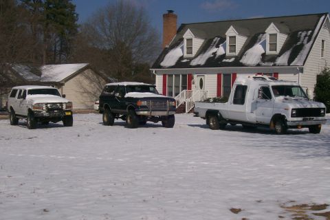 1988 Ford Bronco - Three Ford Broncos and a truck are parked in a snowy yard in front of a house.