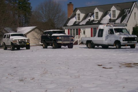 1988 Ford Bronco - A black Ford Bronco with a lifted suspension sits in the snow, parked in front of a house.