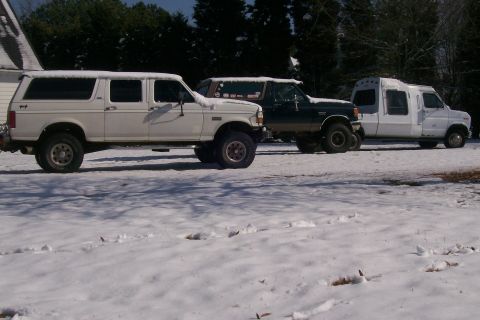1988 Ford Bronco - Three trucks, including a 1988 Ford Bronco, are parked outside in the snow.