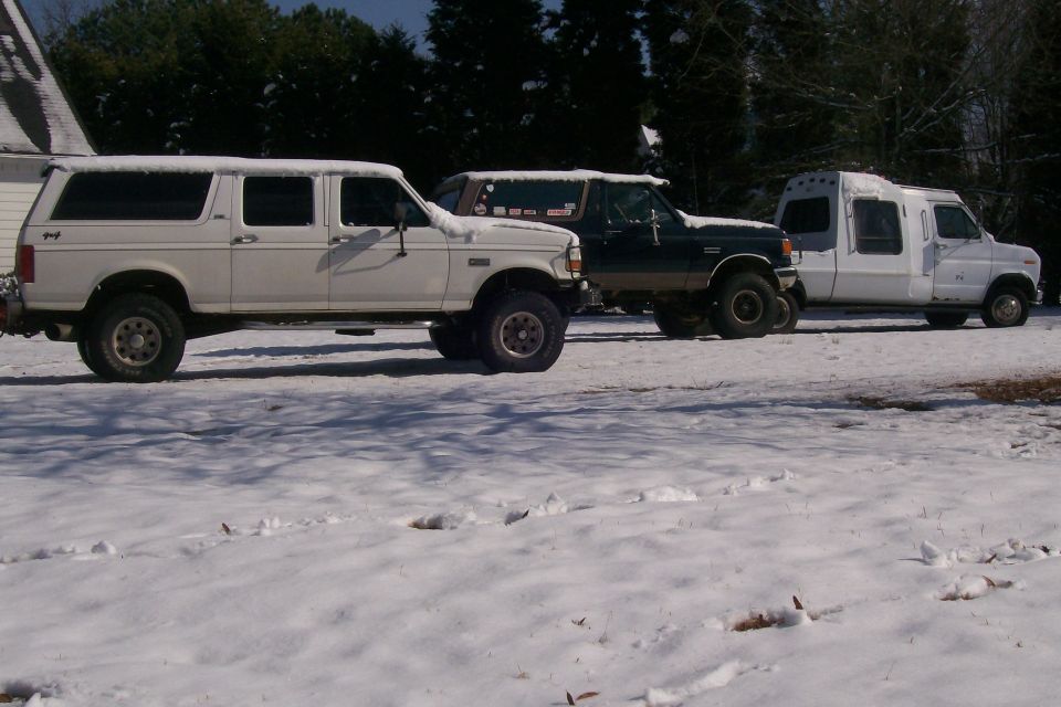 1988 Ford Bronco and two other trucks parked in the snow