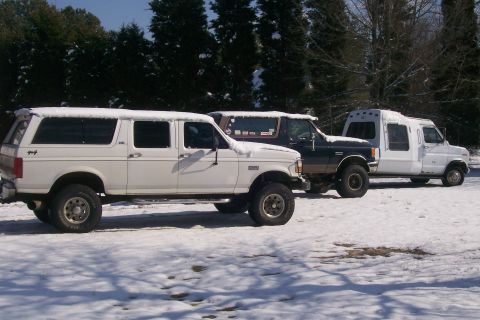 1988 Ford Bronco - Three vehicles, including a dark blue Ford Bronco, are parked in the snow.