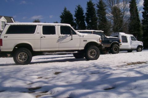 1988 Ford Bronco - Three vehicles, including a white SUV, are parked in a snowy outdoor setting.