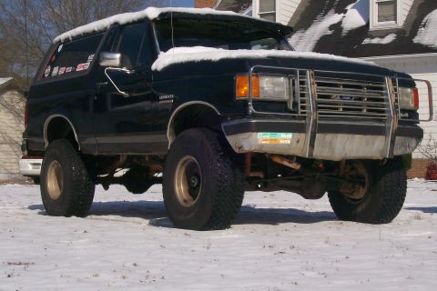 1988 Ford Bronco - This lifted Ford Bronco is covered in snow, suggesting it's winter. The vehicle has aftermarket modifications.