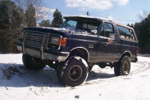 1988 Ford Bronco - This lifted 1988 Ford Bronco is shown in a snowy outdoor setting, a prominent brush guard on its front end.