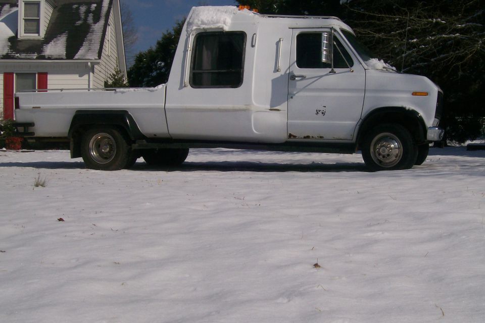 White Ford Econoline van cut down into a pickup, side view parked in snow