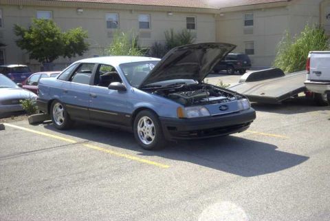 1997 Ford Taurus - Blue 1997 Ford Taurus sedan parked with its hood open, showing the engine bay.