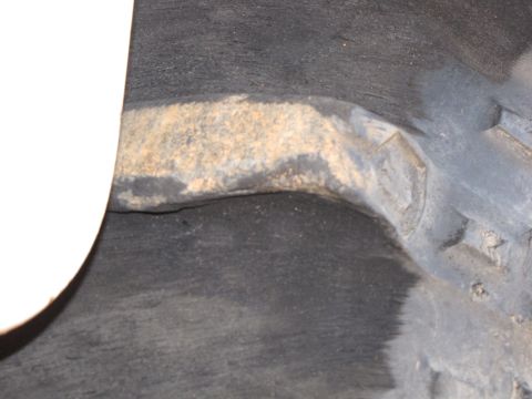 1995 Ford Bronco - A close-up view of a vehicle's wheel well shows a rusty suspension component against a dark background.