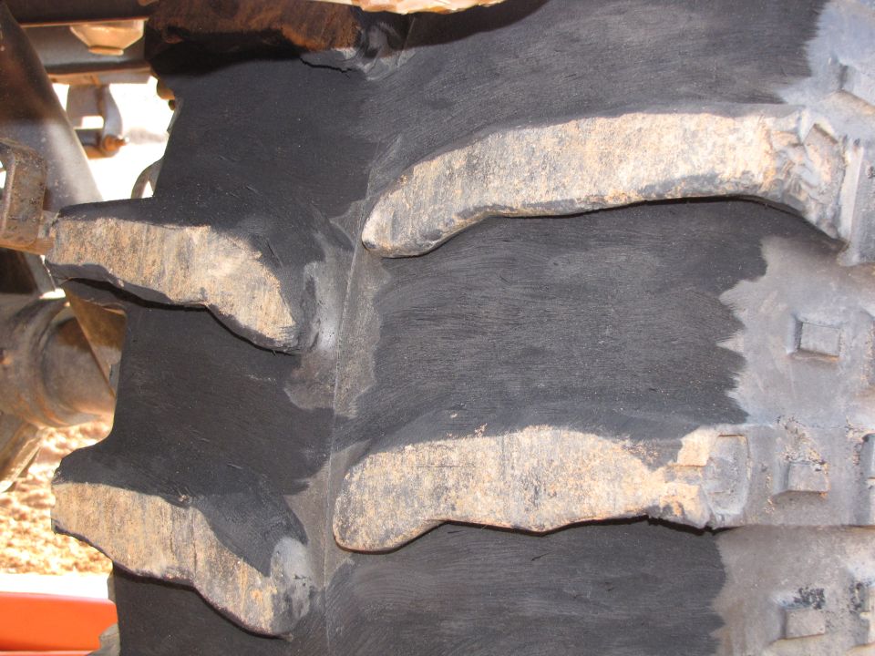 Close-up of a large, aggressive tire tread with mud caked on the lugs