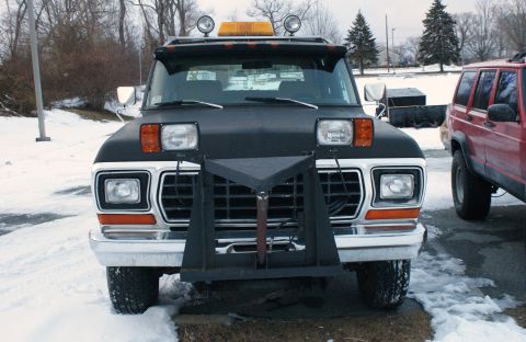1979 Ford Bronco - Front view of a black 1979 Ford Bronco equipped with a snow plow and auxiliary lights, parked outdoors in a snowy environment.