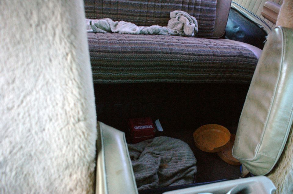 Interior view showing patterned seats, a blanket, a red box with 'STANDARD' text, and orange objects on the floor