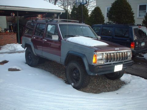 1989 Ford Bronco - A two-tone Jeep Cherokee XJ sits in the snow, with another dark SUV parked behind it.