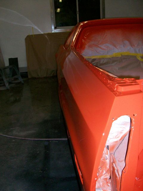 1973 Ford Ranchero - A car body is being spray painted orange, with masking tape visible around the edges.