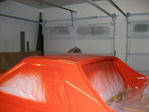 1973 Ford Ranchero - The orange 1973 Ford Ranchero is covered in plastic and being painted in a garage.