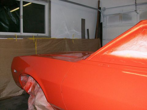 1973 Ford Ranchero - Freshly sprayed bright orange body panels in a home garage paint booth, showing the passenger-side front fender, hood and cowl of a car wit…