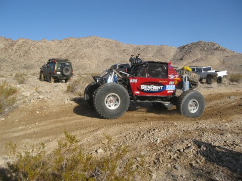 1986 Ford Bronco - Multiple off-road vehicles navigate a desert terrain under a clear blue sky.
