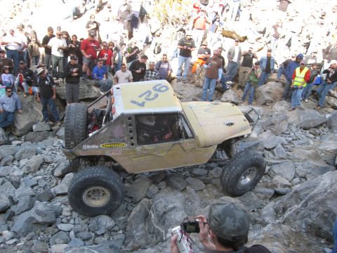 1986 Ford Bronco - A heavily modified off-road vehicle tackles a challenging rocky terrain while spectators observe the action.