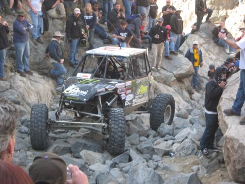 1986 Ford Bronco - A custom off-road buggy tackles a challenging rocky course with a crowd watching.
