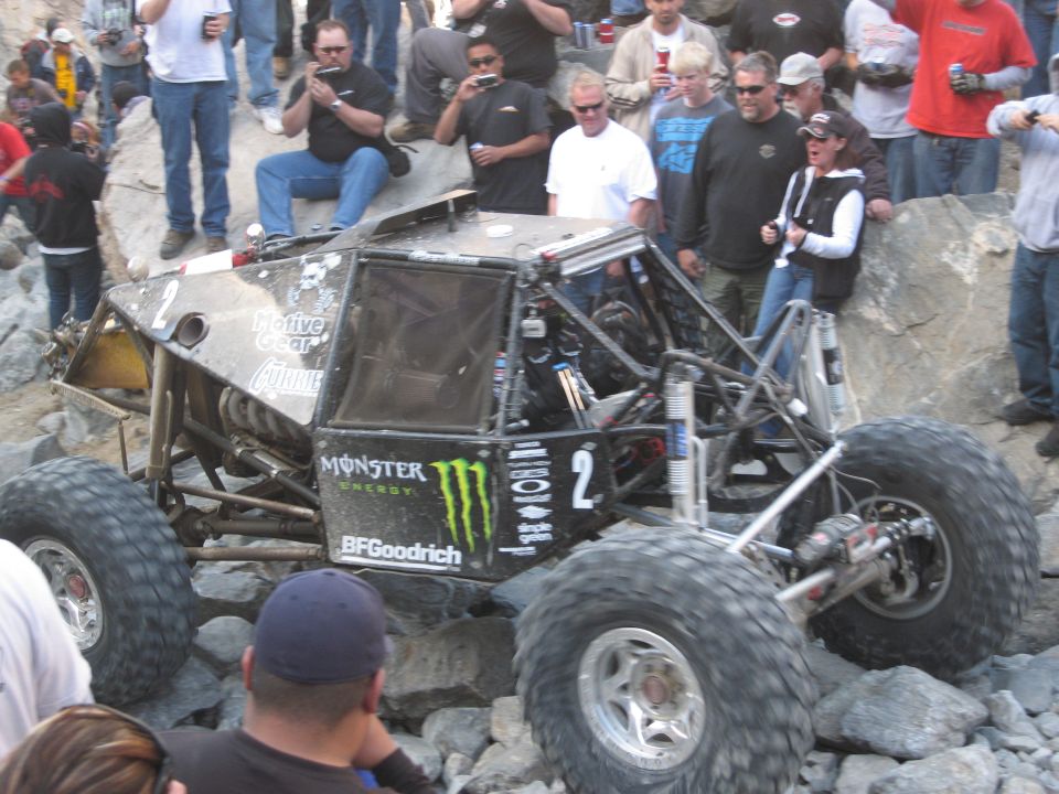 Off-road buggy with large tires and Monster Energy logos navigating rocky terrain, number 2 visible