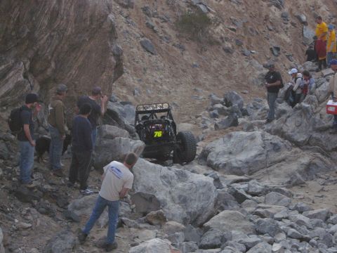 1986 Ford Bronco - Spectators watch as a buggy tackles a challenging rocky course during an off-road event.