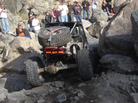 1986 Ford Bronco - An off-road vehicle tackles a challenging rocky course with spectators observing the action.