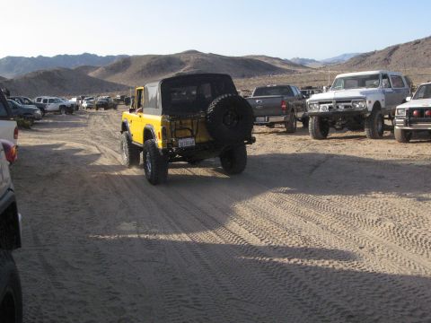 1986 Ford Bronco - A yellow 1978 Ford Bronco is seen from the rear in a desert landscape with other vehicles.