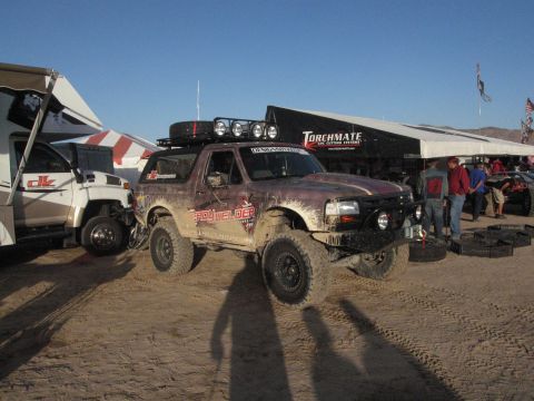 1986 Ford Bronco - This modified Ford Bronco, likely from the early to mid-1990s, is seen at an outdoor event with other vehicles and tents.