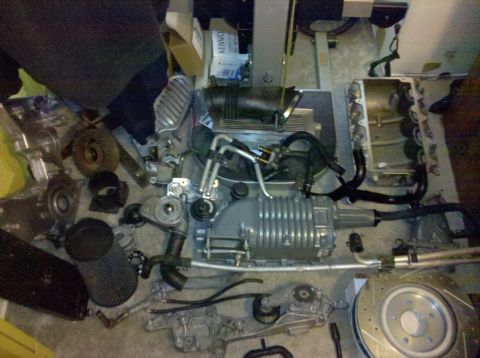 1992 Ford Bronco - Various engine components are disassembled and arranged on the floor, suggesting a repair or upgrade project.