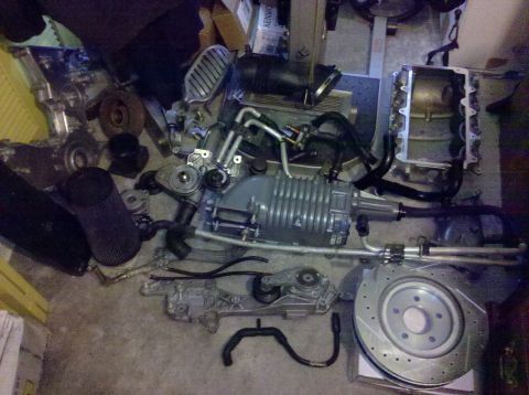 1992 Ford Bronco - Various engine parts, including a supercharger and brake rotor, are laid out on a floor.