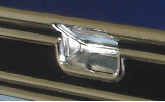 1979 Ford F-250 - A chrome emblem is shown on the horizontal bars of a vehicle's grille, with a SuperMotors logo in the corner.