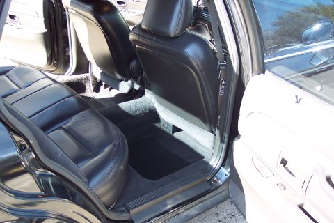2001 Ford Crown Victoria - Rear interior view of a 2001 Ford Crown Victoria, showing black leather seats and door panel.