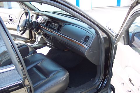 2001 Ford Crown Victoria - The interior of a 2001 Ford Crown Victoria is shown, black leather seats and a dark dashboard with wood trim accents.