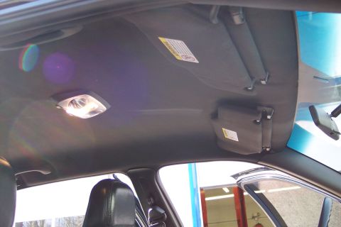 2001 Ford Crown Victoria - The interior ceiling of a vehicle is shown, including the dome light and sun visors with warning labels.