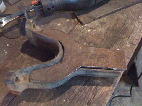 1989 Ford Bronco - A metal component, possibly a bracket or mount, rests on a workbench with 'TOP' marked on its surface.