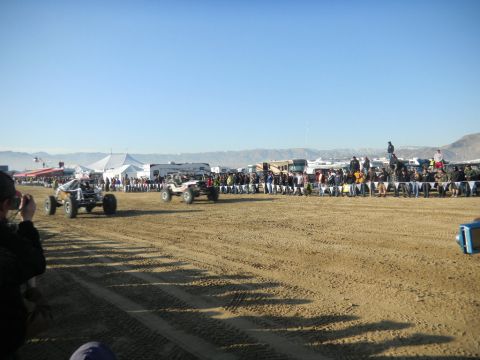 1997 Ford Ranger - Off-road vehicles compete on a dusty track with crowds and tents lining the course.