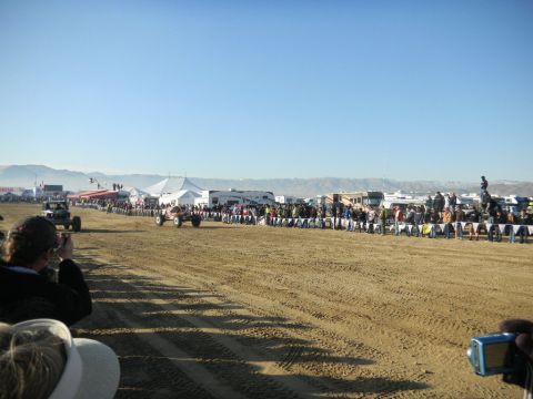 1997 Ford Ranger - Spectators watch off-road vehicles compete on a sandy track with tents and RVs in the background.
