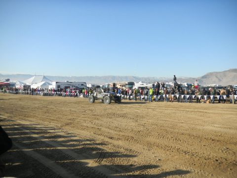 1997 Ford Ranger - A crowd watches an off-road race with tents and RVs in the background under a clear blue sky.