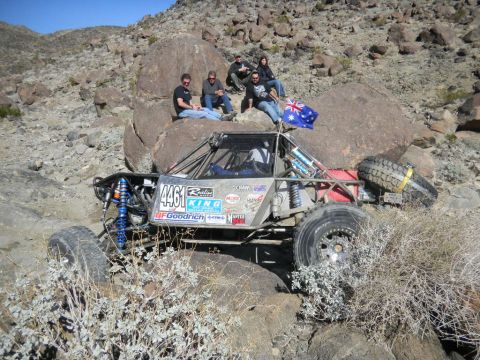 1997 Ford Ranger - A custom-built off-road buggy with racing decals sits in a rocky desert landscape with several people watching.